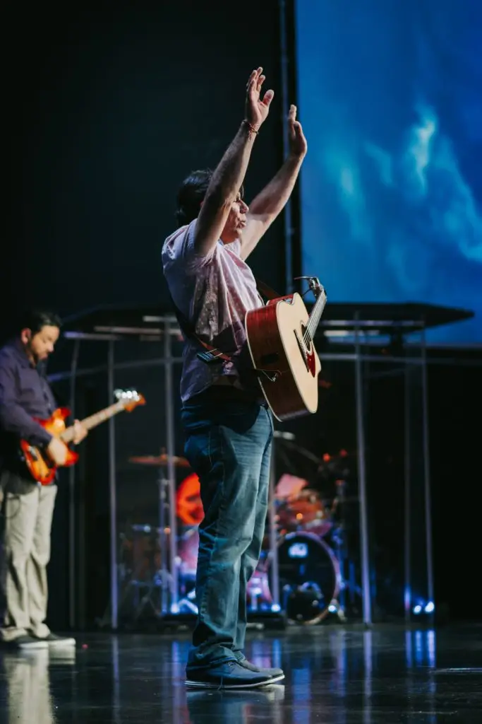 Musicians performing energetically on stage with guitars and drums.