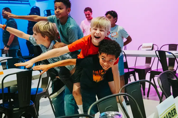 Children joyfully playing and balancing in a lively classroom setting.