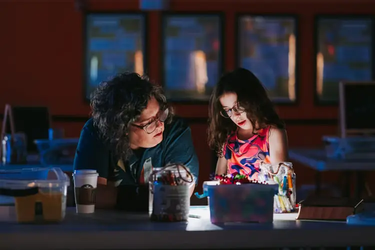 Parent and child bonding over arts and crafts at a cozy table.