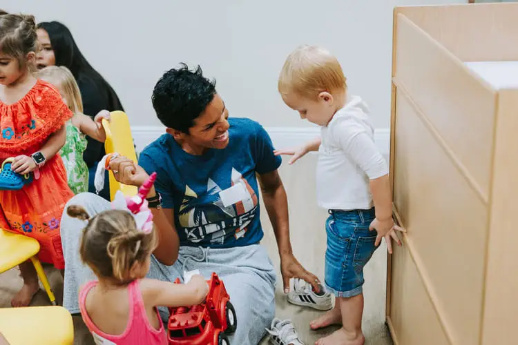 A man and children playing with toys indoors.