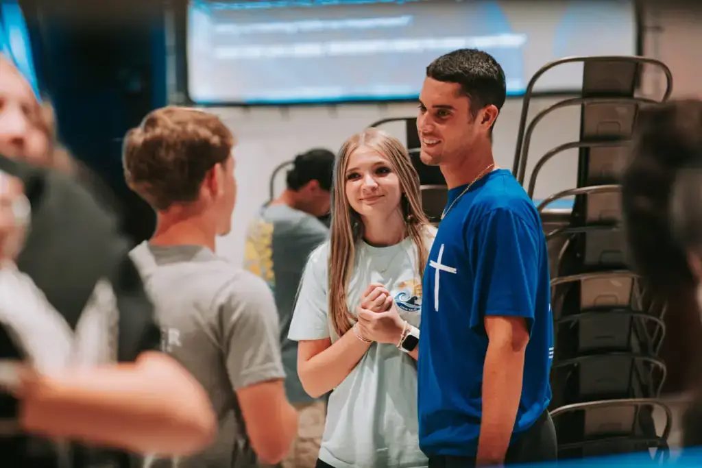 Three young people chatting and smiling indoors.