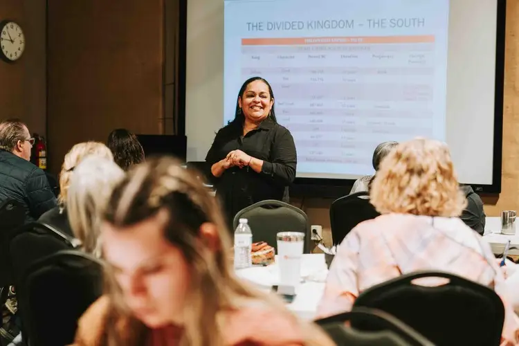 A woman confidently presents in front of an audience at a seminar.