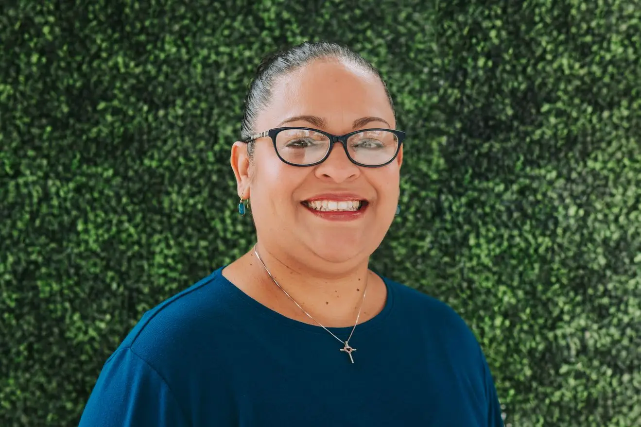 Smiling person in front of green foliage.